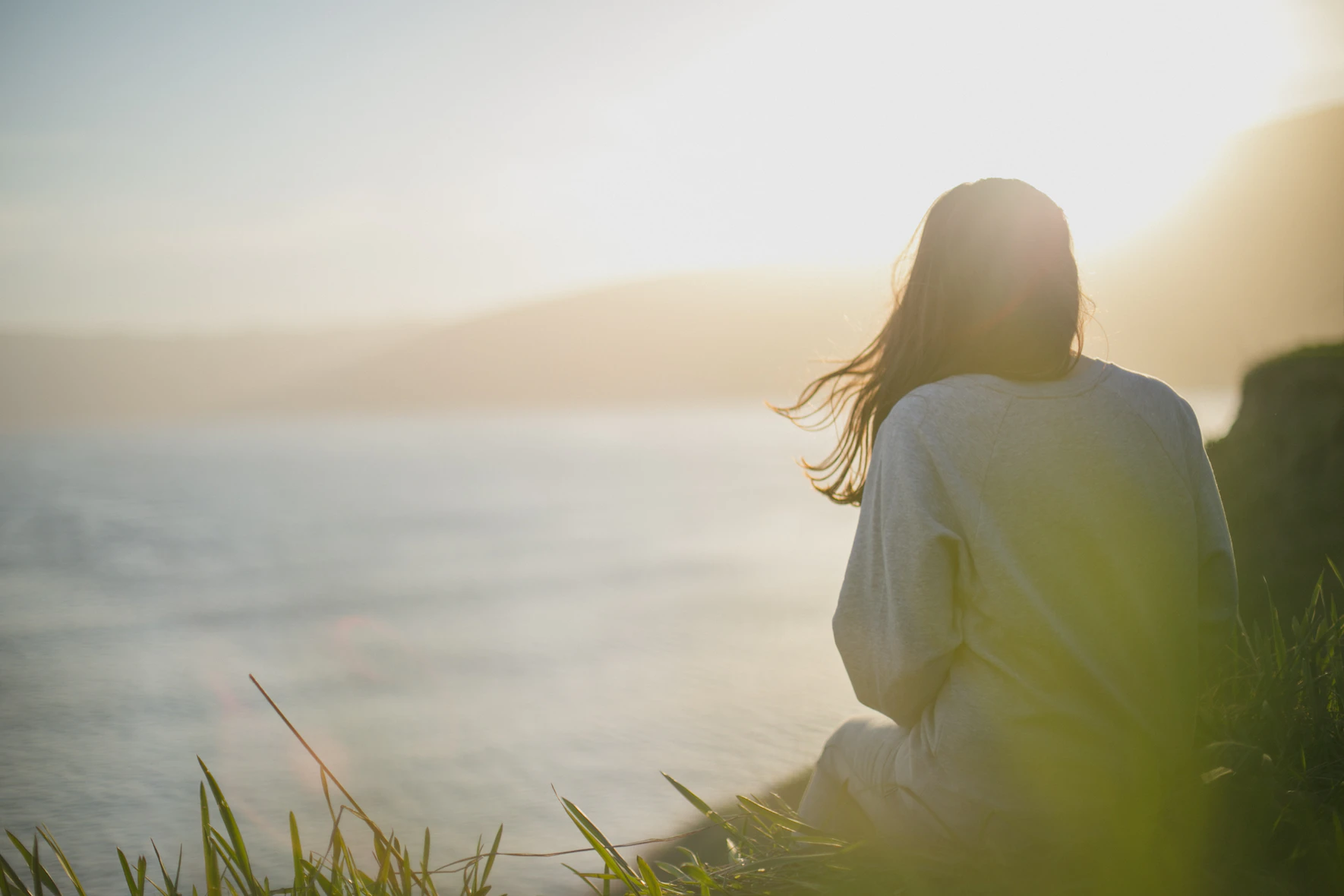 women sitting on edge of ocean